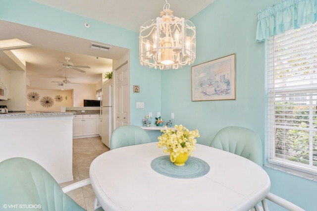 tiled dining area with ceiling fan with notable chandelier