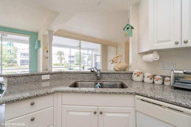 kitchen featuring kitchen peninsula, sink, white dishwasher, white cabinetry, and light stone countertops