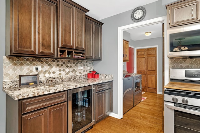 kitchen with light hardwood / wood-style flooring, decorative backsplash, wine cooler, light stone counters, and dark brown cabinetry