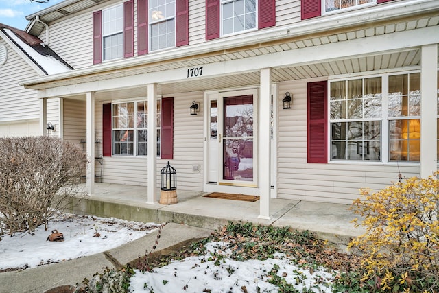 snow covered property entrance with a porch