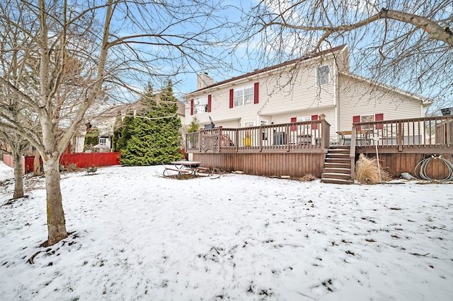 snow covered back of property with a deck