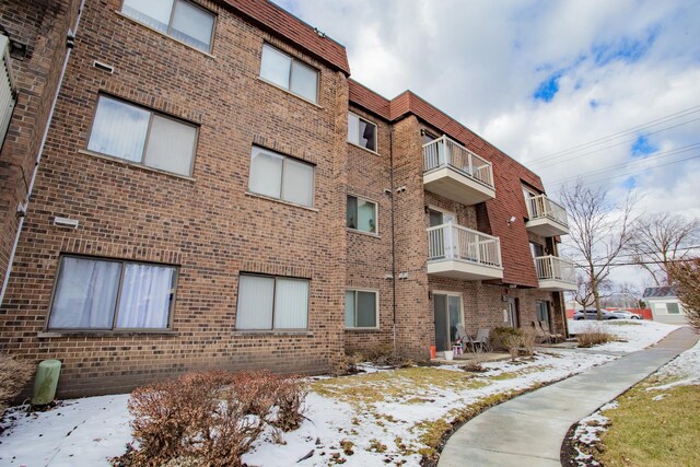 snow covered property entrance with a balcony and elevator