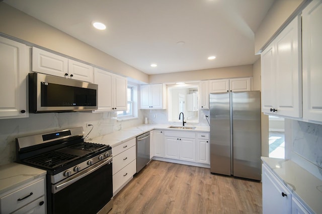 kitchen featuring appliances with stainless steel finishes, sink, white cabinets, and light hardwood / wood-style floors