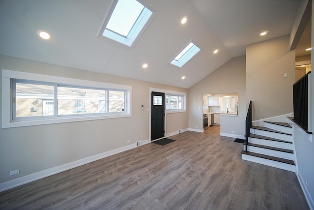 entryway featuring dark hardwood / wood-style floors, sink, high vaulted ceiling, and a skylight