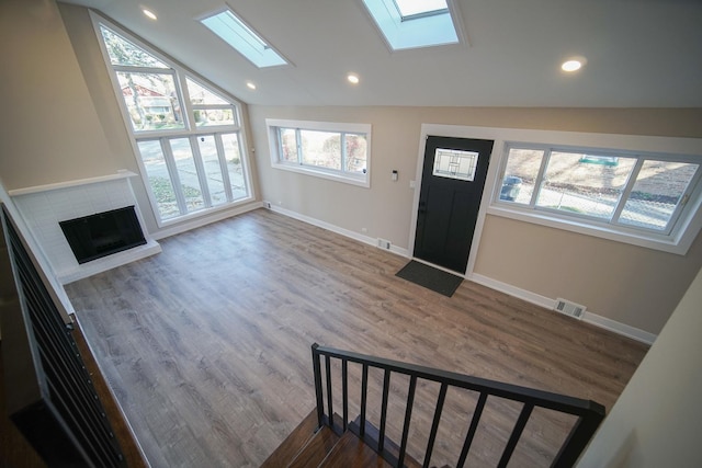 entryway with lofted ceiling with skylight and wood-type flooring