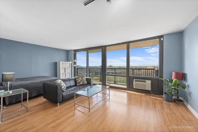 living room featuring light wood-type flooring, plenty of natural light, an AC wall unit, and floor to ceiling windows