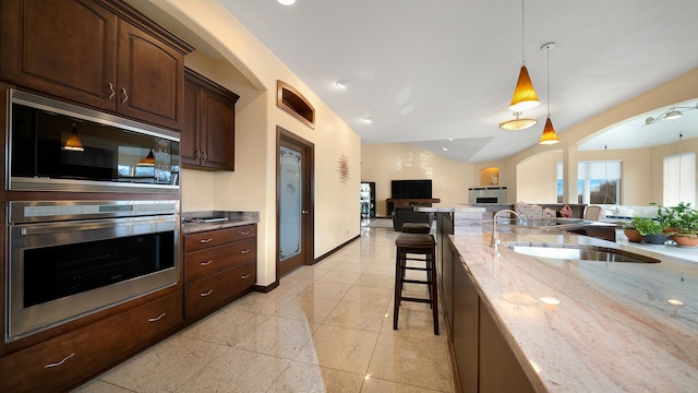 kitchen featuring a breakfast bar, black microwave, sink, hanging light fixtures, and stainless steel oven