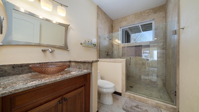 bathroom with a shower with door, vanity, tile patterned flooring, and toilet