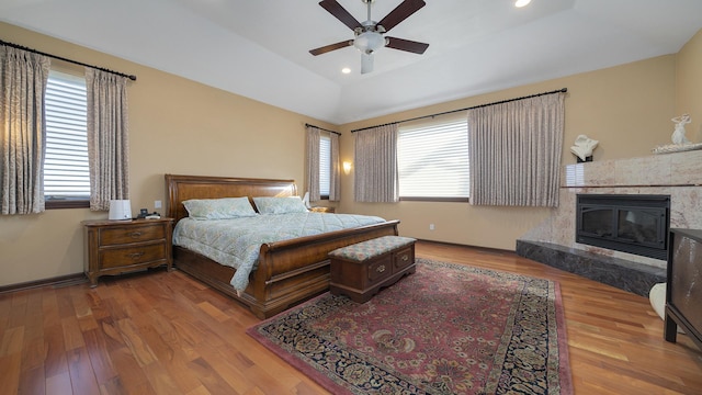 bedroom with hardwood / wood-style floors, a fireplace, ceiling fan, and vaulted ceiling