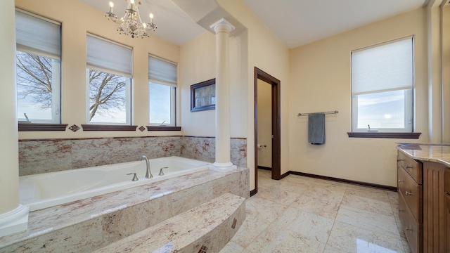 bathroom featuring vanity, tiled bath, decorative columns, and a notable chandelier