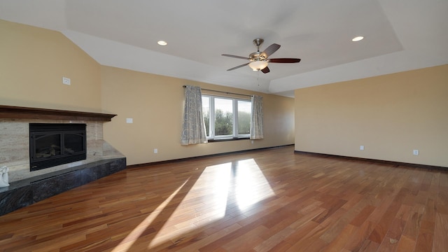 unfurnished living room with a raised ceiling, vaulted ceiling, hardwood / wood-style floors, and ceiling fan