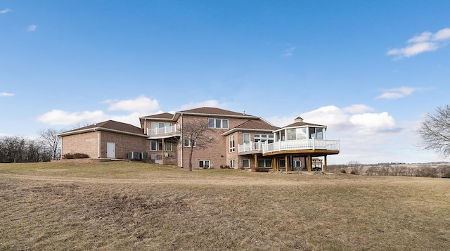 back of property with a wooden deck, central AC unit, and a lawn