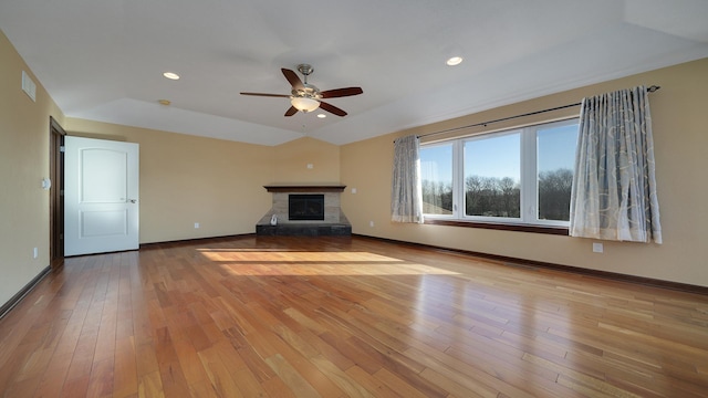 unfurnished living room featuring vaulted ceiling, a stone fireplace, ceiling fan, and light hardwood / wood-style flooring