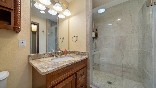 bathroom with vanity, a shower with door, and toilet