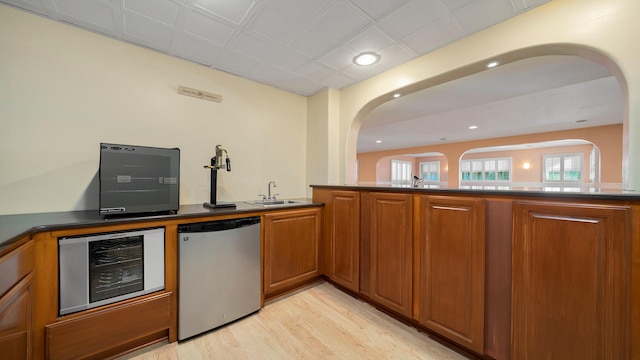 kitchen featuring sink, dishwasher, fridge, wine cooler, and light hardwood / wood-style floors