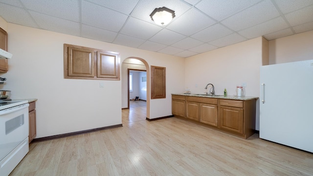 kitchen with a drop ceiling, sink, white appliances, and light wood-type flooring