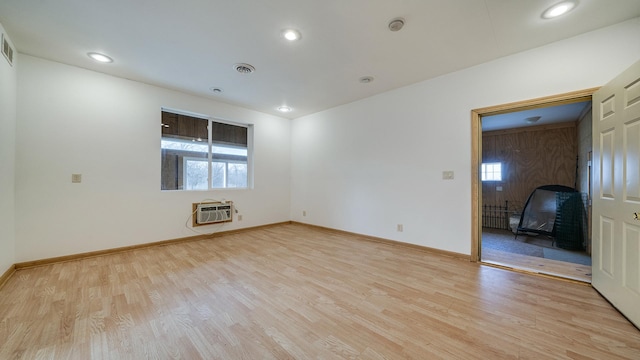 empty room with light hardwood / wood-style floors and an AC wall unit