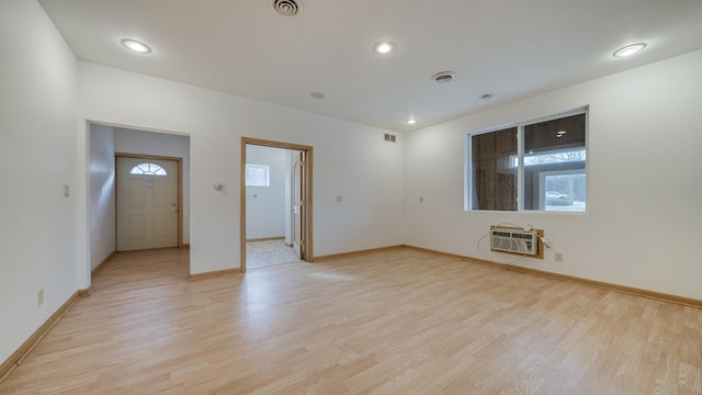 interior space featuring a wall mounted air conditioner and light hardwood / wood-style flooring