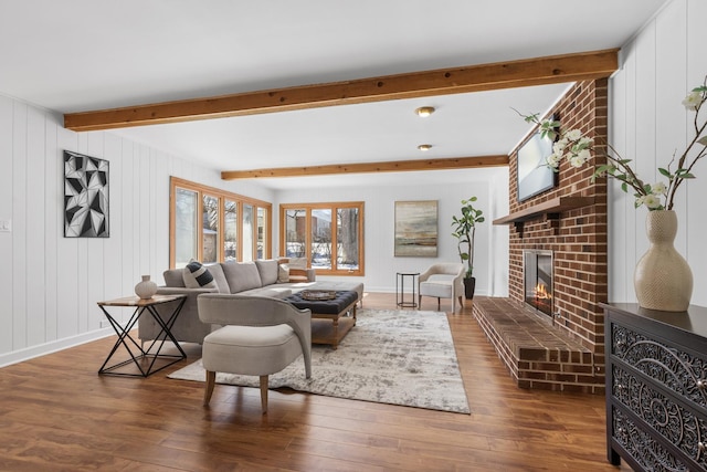 living room featuring dark wood finished floors, baseboards, a fireplace, and beamed ceiling