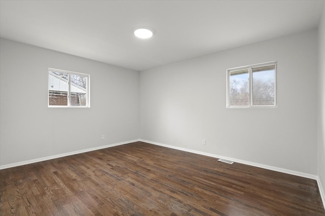 spare room with dark hardwood / wood-style flooring and plenty of natural light