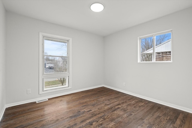 empty room with dark hardwood / wood-style flooring and plenty of natural light