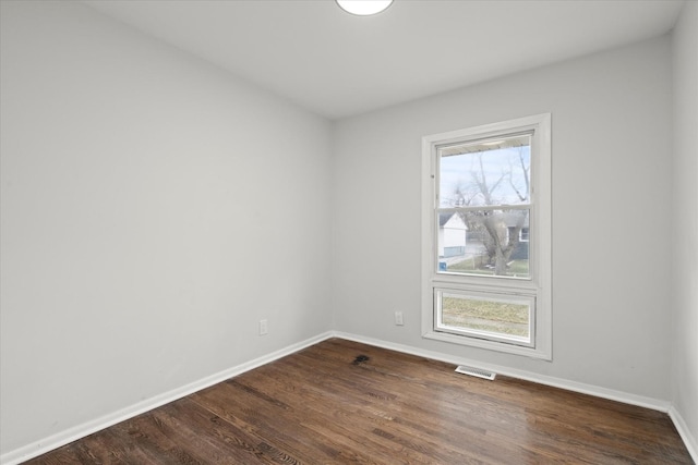 empty room with dark wood-type flooring and a wealth of natural light