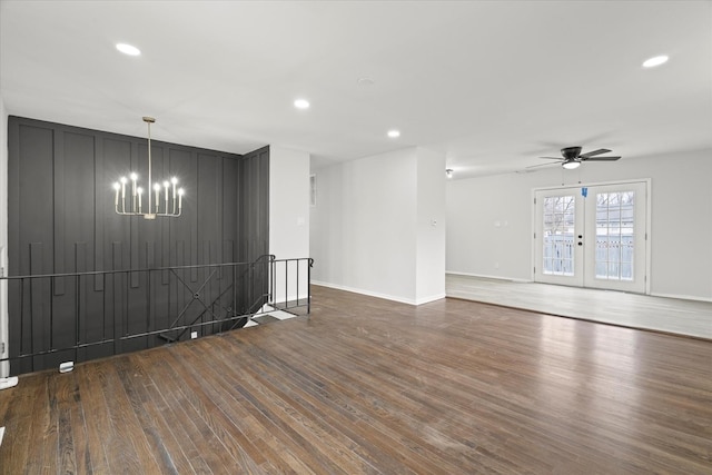 empty room featuring dark wood-type flooring, ceiling fan with notable chandelier, and french doors