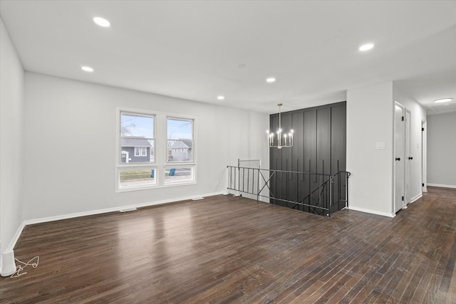 unfurnished room with an inviting chandelier and dark hardwood / wood-style floors