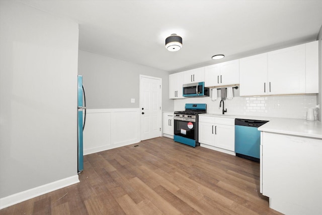 kitchen featuring hardwood / wood-style flooring, appliances with stainless steel finishes, white cabinets, and backsplash