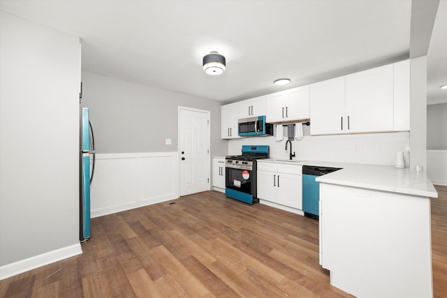 kitchen with hardwood / wood-style flooring, appliances with stainless steel finishes, sink, and white cabinets