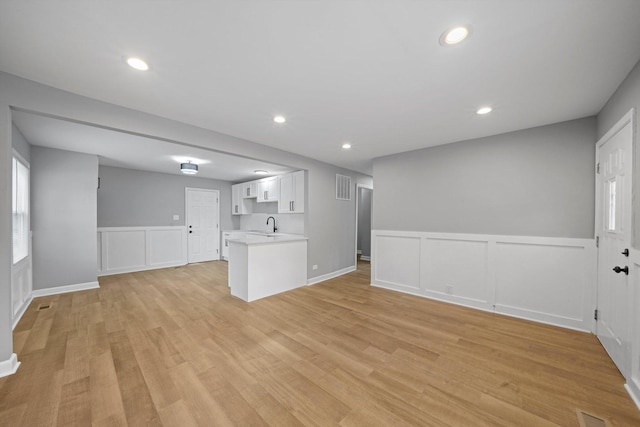 unfurnished living room with sink and light hardwood / wood-style floors