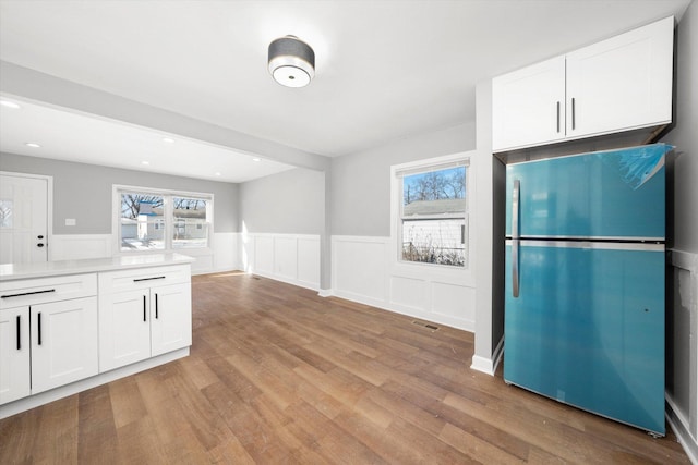 kitchen with white cabinetry, light wood-type flooring, and refrigerator