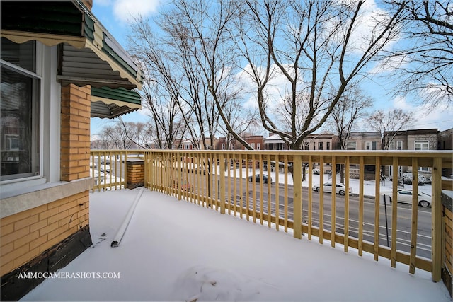 snow covered patio with a wooden deck