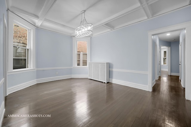 spare room with dark hardwood / wood-style floors, an inviting chandelier, coffered ceiling, and beamed ceiling