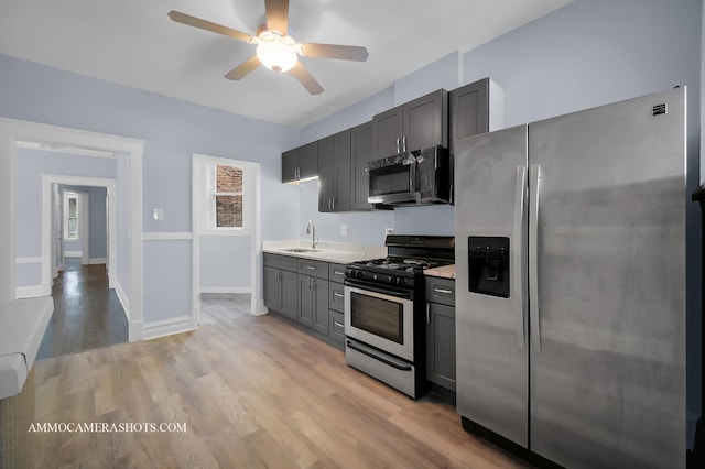 kitchen with appliances with stainless steel finishes, sink, light wood-type flooring, ceiling fan, and gray cabinetry