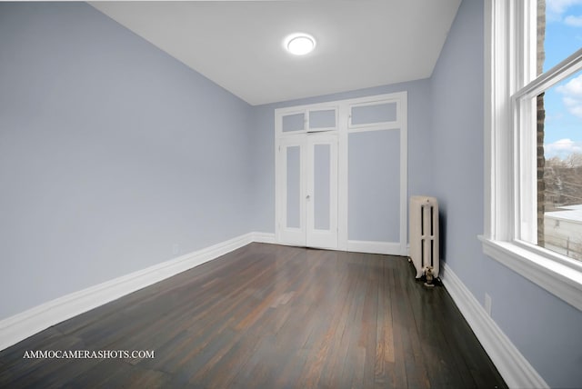 spare room featuring dark wood-type flooring and radiator heating unit