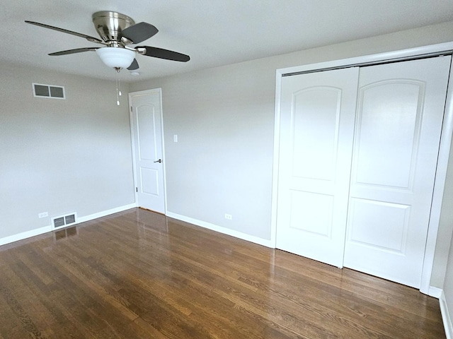 unfurnished bedroom with ceiling fan, dark hardwood / wood-style flooring, and a closet