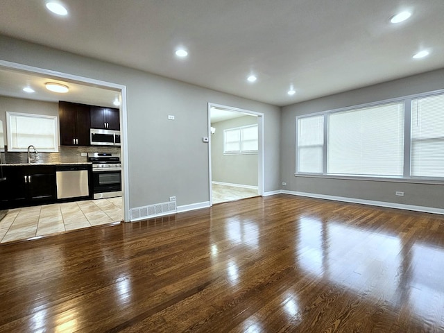 unfurnished living room with light hardwood / wood-style flooring and sink