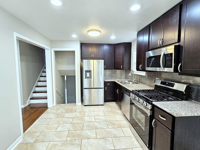 kitchen featuring dark brown cabinetry, appliances with stainless steel finishes, decorative backsplash, sink, and light tile patterned flooring