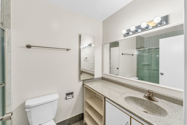 bathroom featuring toilet, vanity, and a shower with door