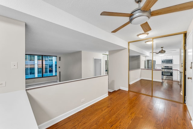 interior space featuring ceiling fan, a textured ceiling, and hardwood / wood-style flooring