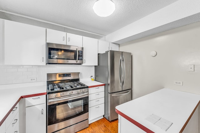 kitchen with decorative backsplash, white cabinetry, light hardwood / wood-style flooring, a textured ceiling, and stainless steel appliances