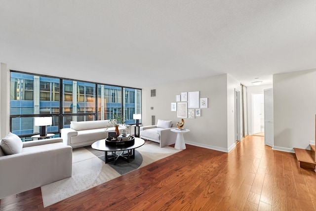 living room featuring light wood-type flooring and a wall of windows