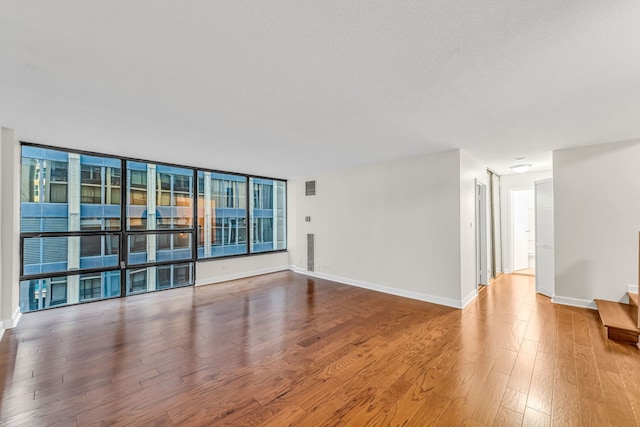 unfurnished room with floor to ceiling windows and wood-type flooring