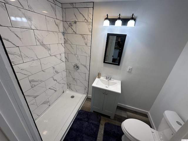 bathroom with vanity, toilet, and a tile shower