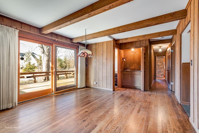 unfurnished dining area with hardwood / wood-style flooring, wood walls, and beamed ceiling