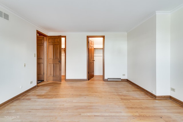 unfurnished bedroom featuring a spacious closet, a closet, ornamental molding, and light wood-type flooring