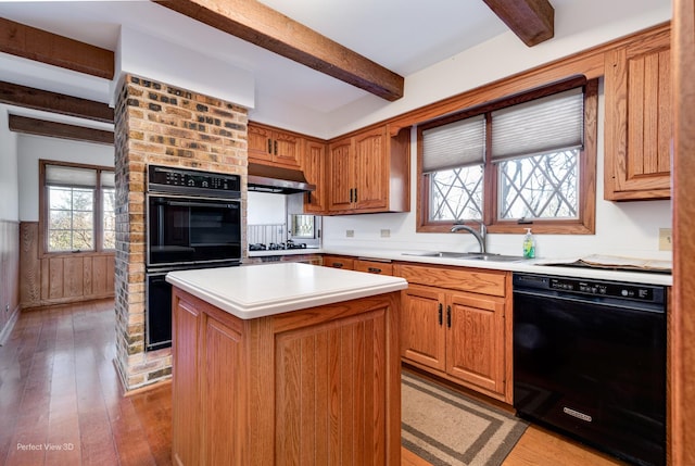 kitchen with exhaust hood, beamed ceiling, a center island, and black appliances