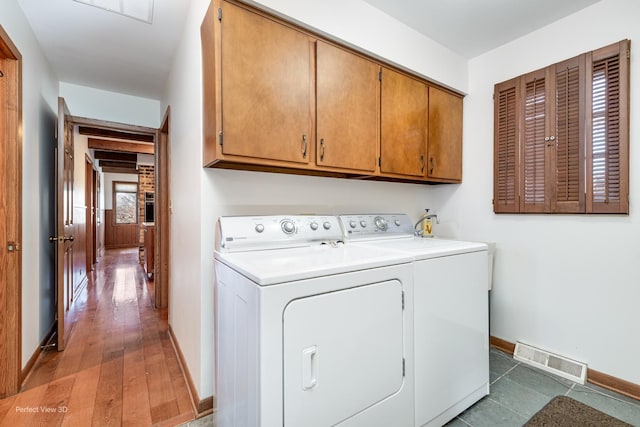 clothes washing area featuring cabinets and separate washer and dryer