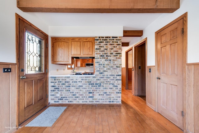 kitchen featuring light hardwood / wood-style flooring, beam ceiling, and wooden walls